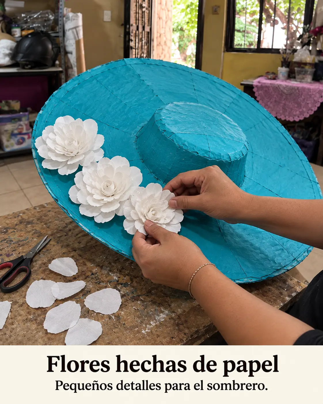 Manos colocando flores de papel blanco en el sombrero turquesa